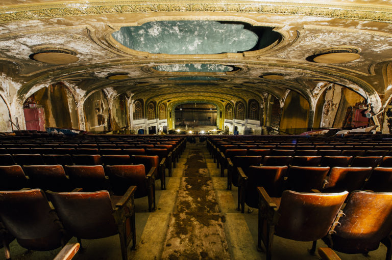 A large auditorium with rows of seats and an empty stage.